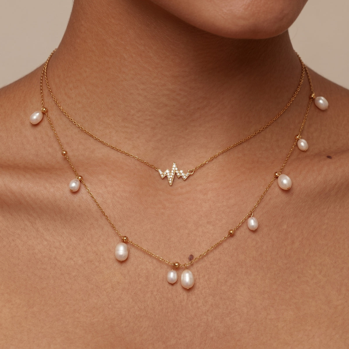 Woman wearing the Giulia pearl cascade necklace, heartbeat charm layered over pearl drops