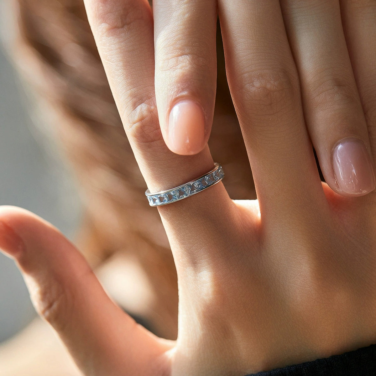 Woman wearing the Sienna blue silver band on a raised hand, its channel-set crystals catching soft light