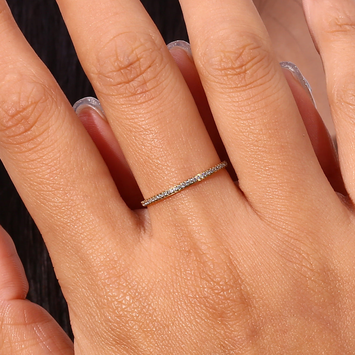 Close view of a hand wearing the Zarra paved gold ring, a fine band with a row of tiny crystals