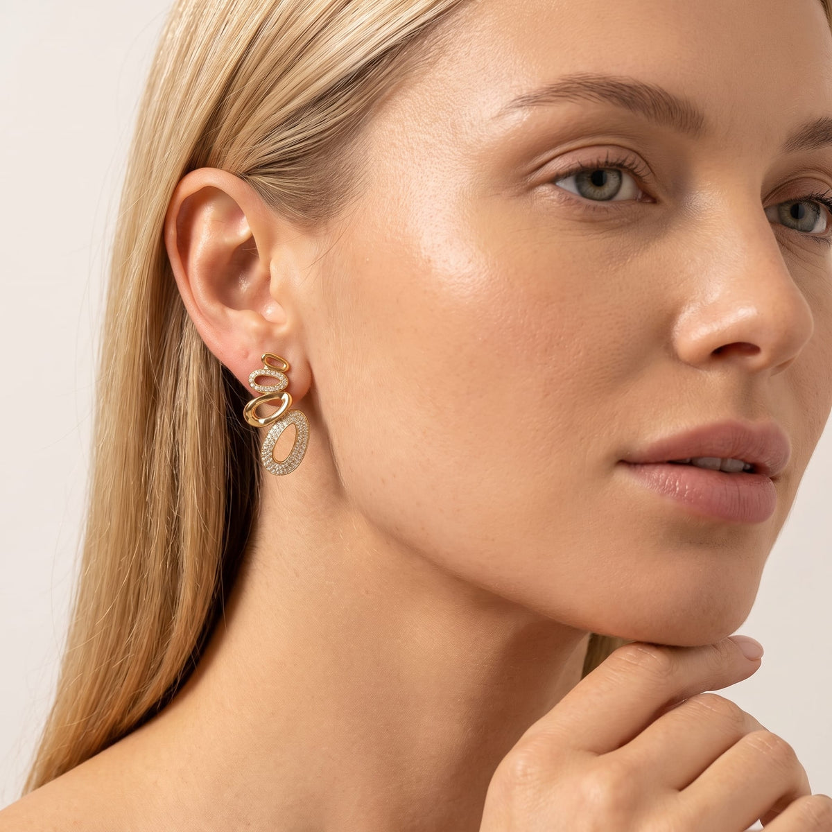 Woman wearing the Agathe pavé oval gold earrings on the ear resting chin on hand