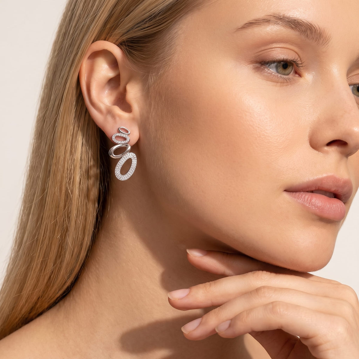Woman wearing the Agathe pavé oval silver earrings on the ear resting her chin on her hand