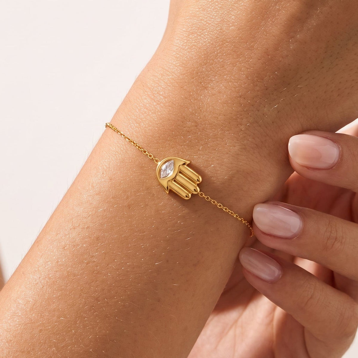 Woman wearing the Amelia crystal hamsa gold bracelet on the wrist
