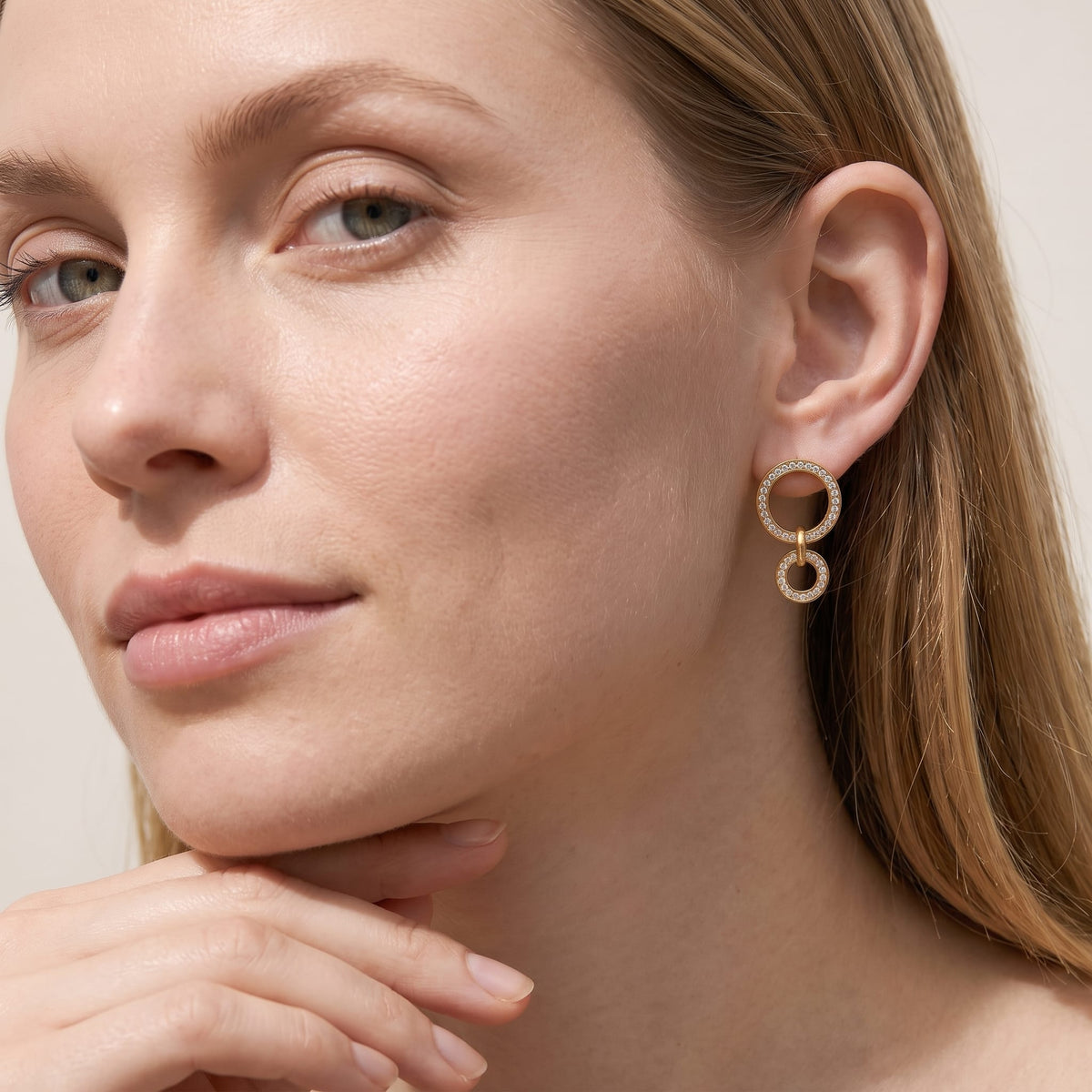 Woman wearing the Apolline double circle gold earrings on the ear resting her chin on her hand