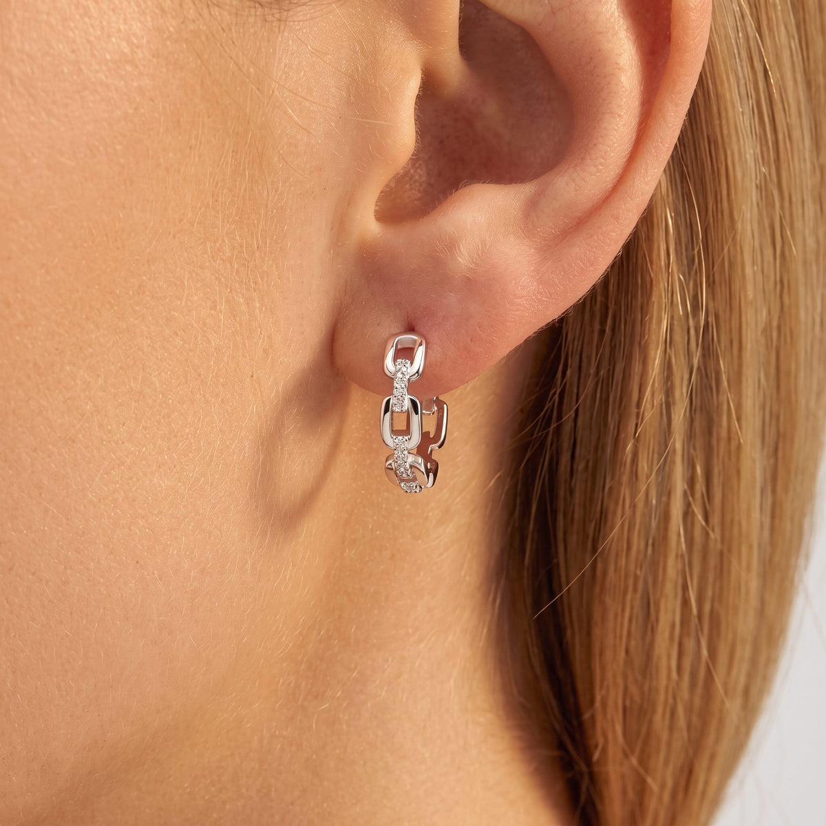 Woman wearing the Ava link silver hoop, small crystal-set chain links hugging the lobe