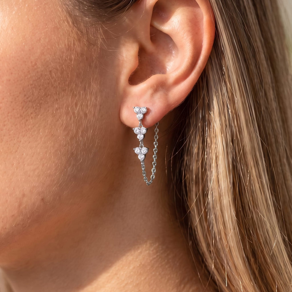 Woman wearing the Bettina crystal cascade silver earrings on her earlobe in sunlight