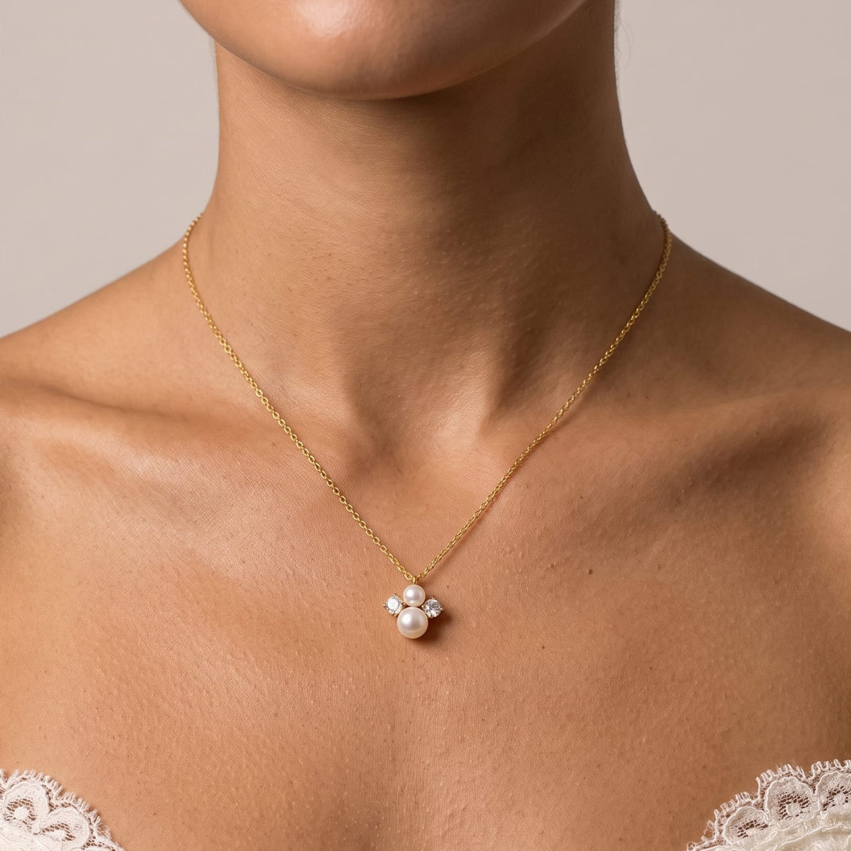 Woman wearing the Blanche pearl cluster gold necklace at the collarbone while dressed in a white lace dress