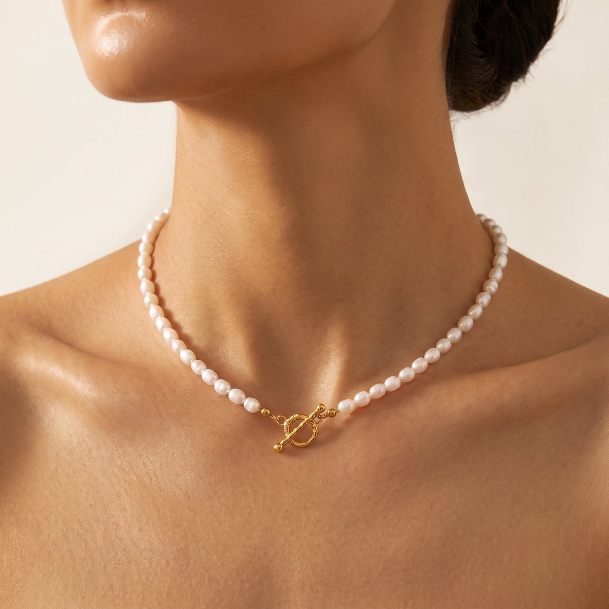 Woman wearing the Camille pearl toggle gold necklace at the collarbone