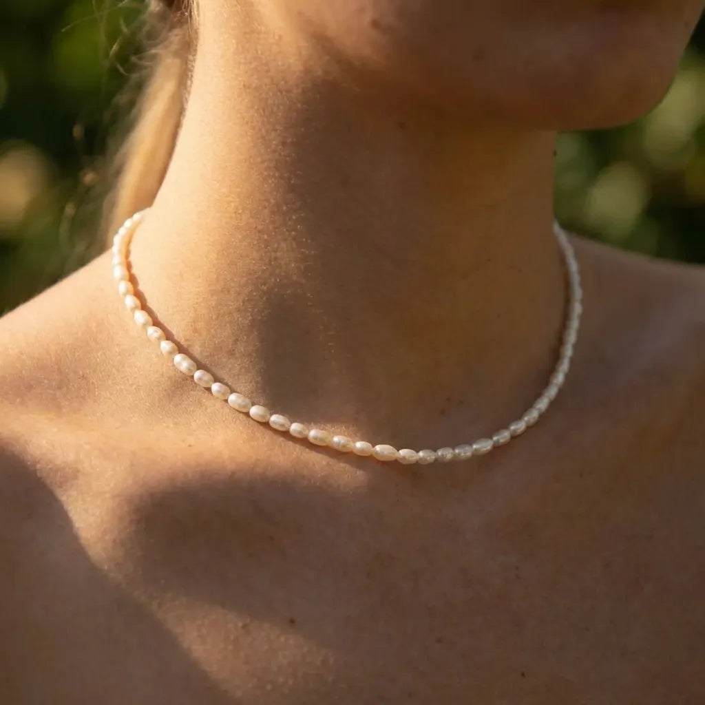Woman wearing the Olivia necklace, a strand of small rice pearls close at the base of the neck