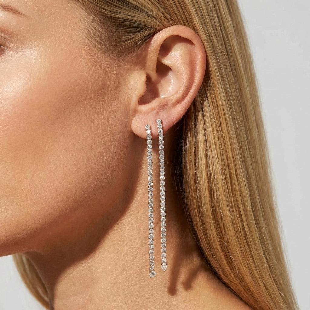 Woman wearing two Camille silver crystal line drop earrings reaching toward the jaw