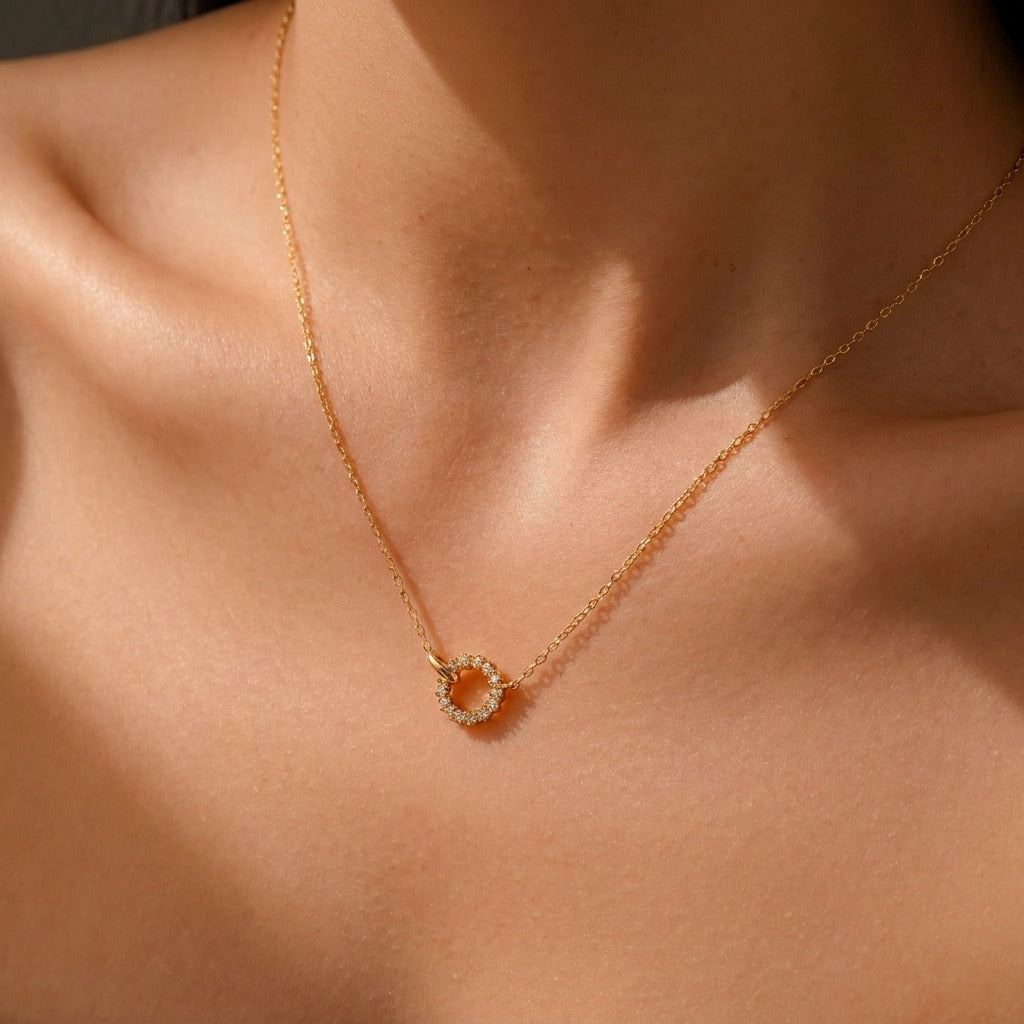 Woman wearing the Isla linked circle necklace in gold, a pavé crystal circle resting at the collarbone