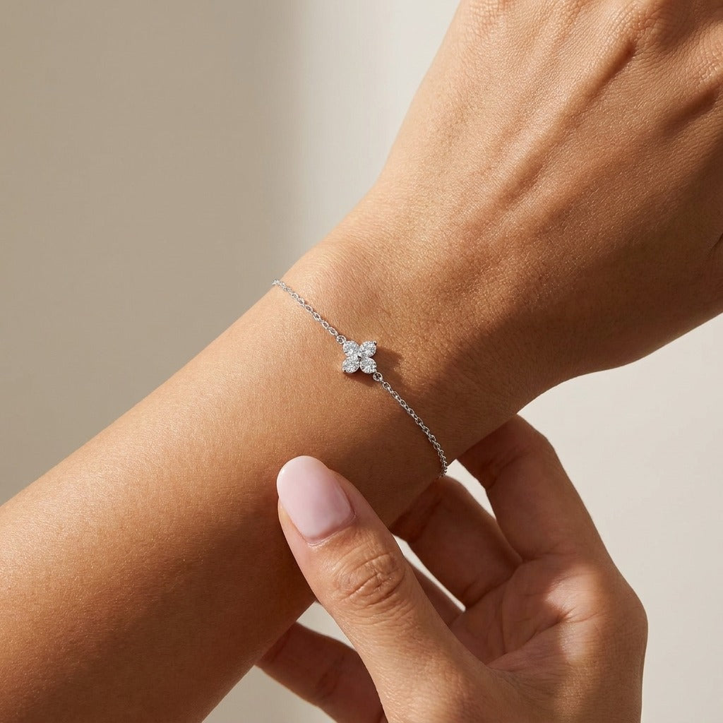 Woman wearing the Camille silver bracelet with a four-petal crystal flower charm on the wrist