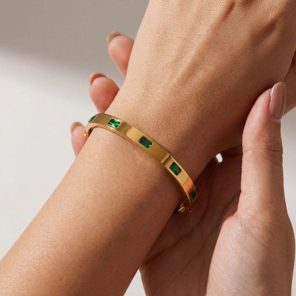 Woman wearing the Hannah gold bangle set with green baguette crystals on the wrist