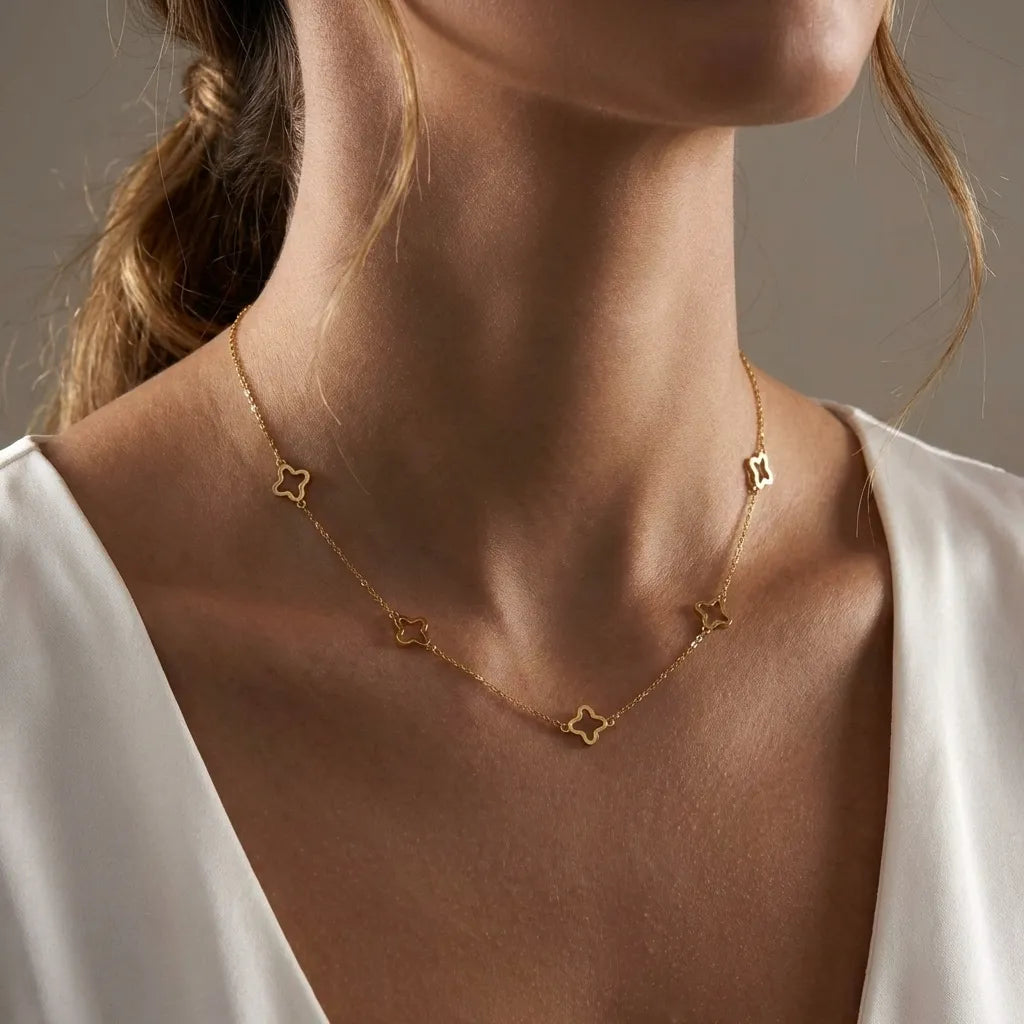Woman in a white top wearing the Inès gold necklace with open clover outlines