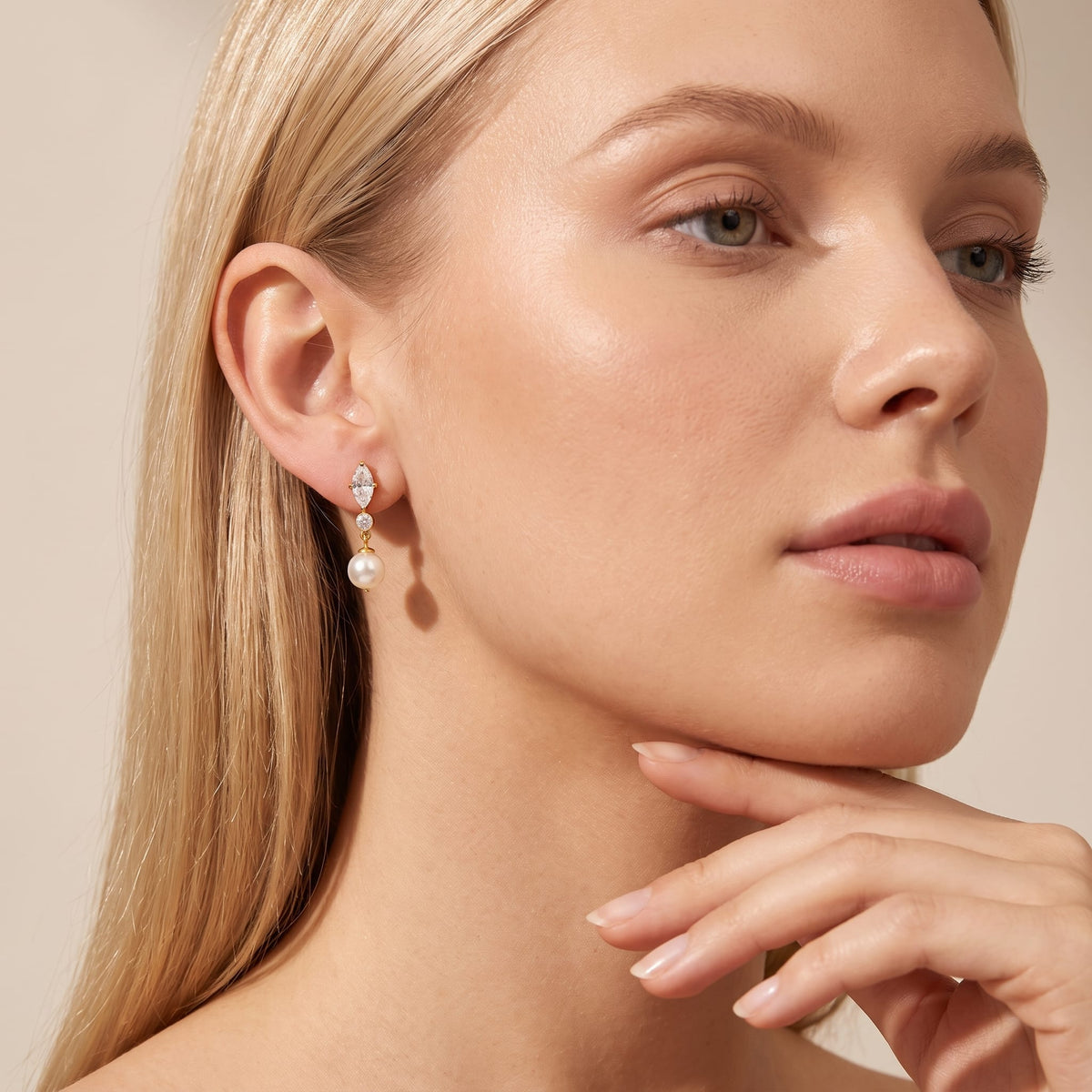 Woman wearing the Emilia marquise pearl gold earrings on her ear with hand near chin