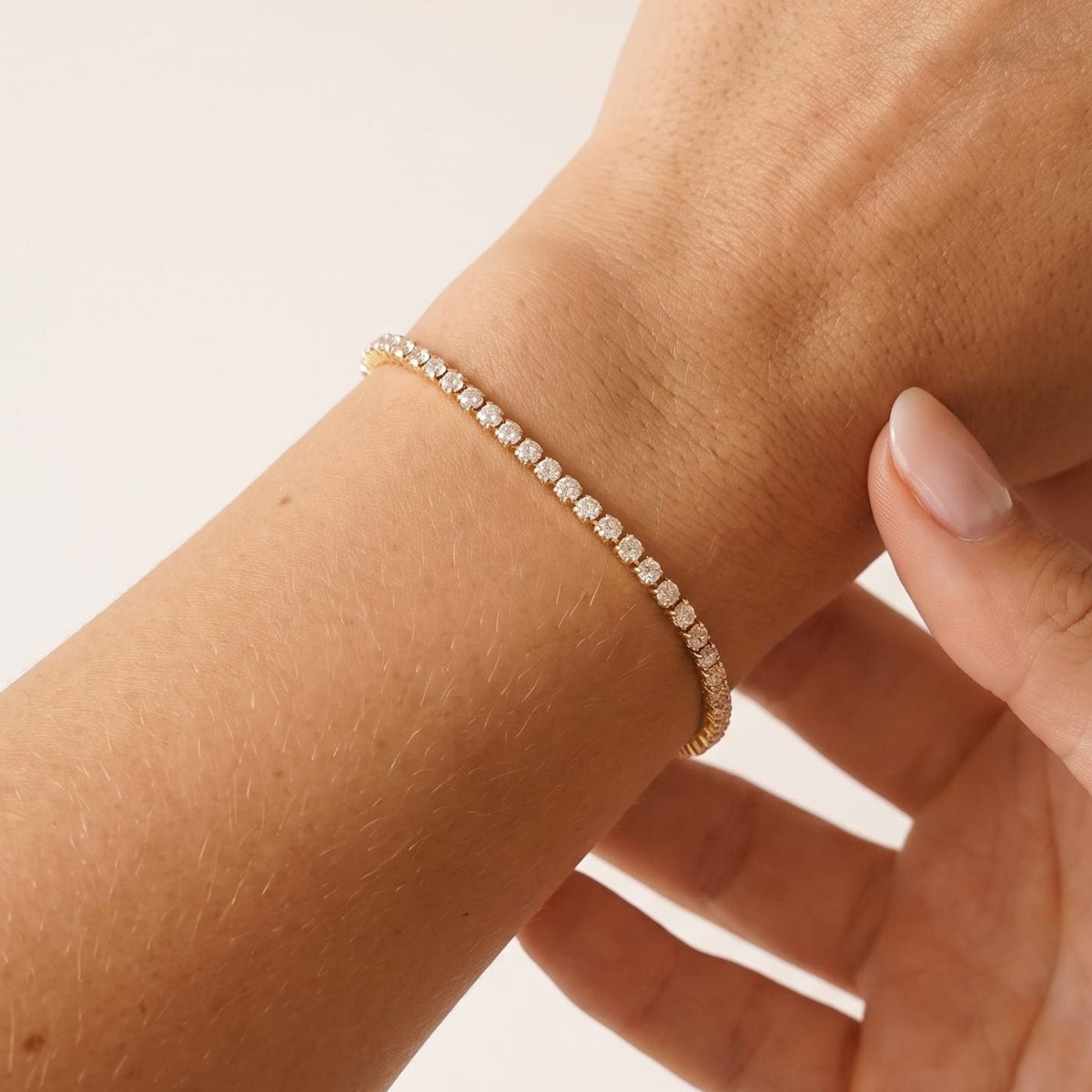 Close-up of the Emma tennis chain gold bracelet on a woman's wrist