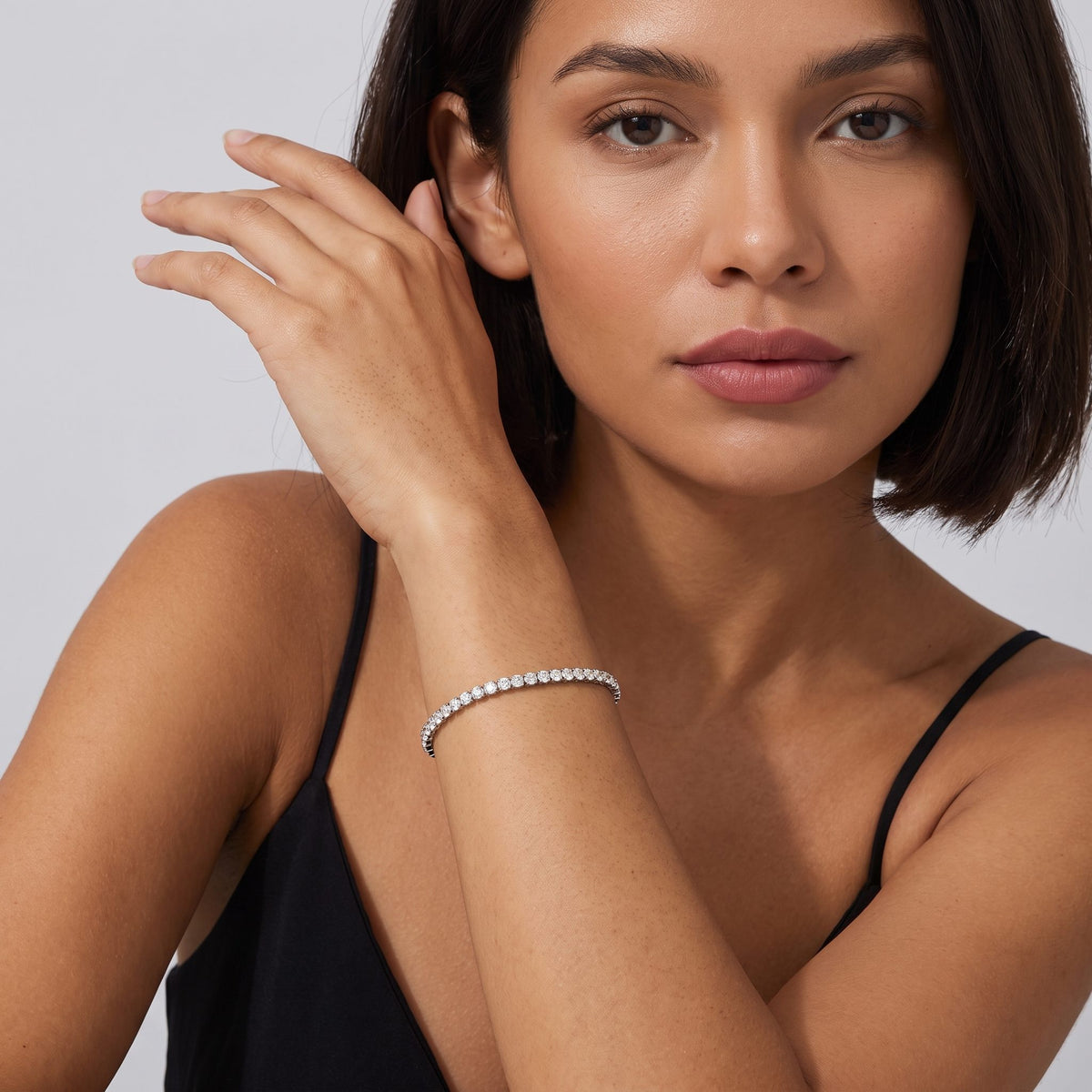 Woman with a dark bob wearing the Emma tennis chain silver bracelet near her chin