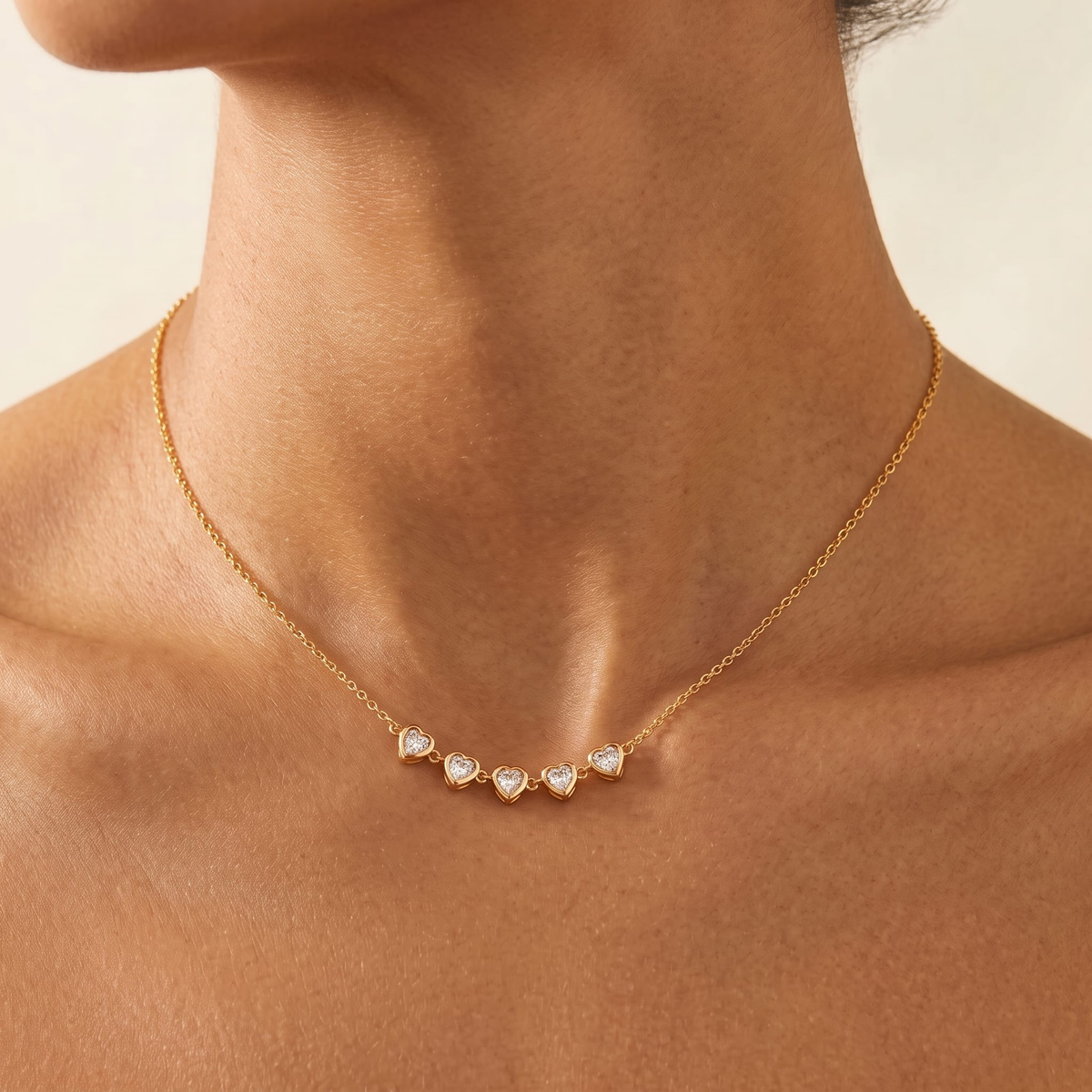 Woman wearing the Evelyne crystal hearts gold necklace at the collarbone, featuring heart pendants