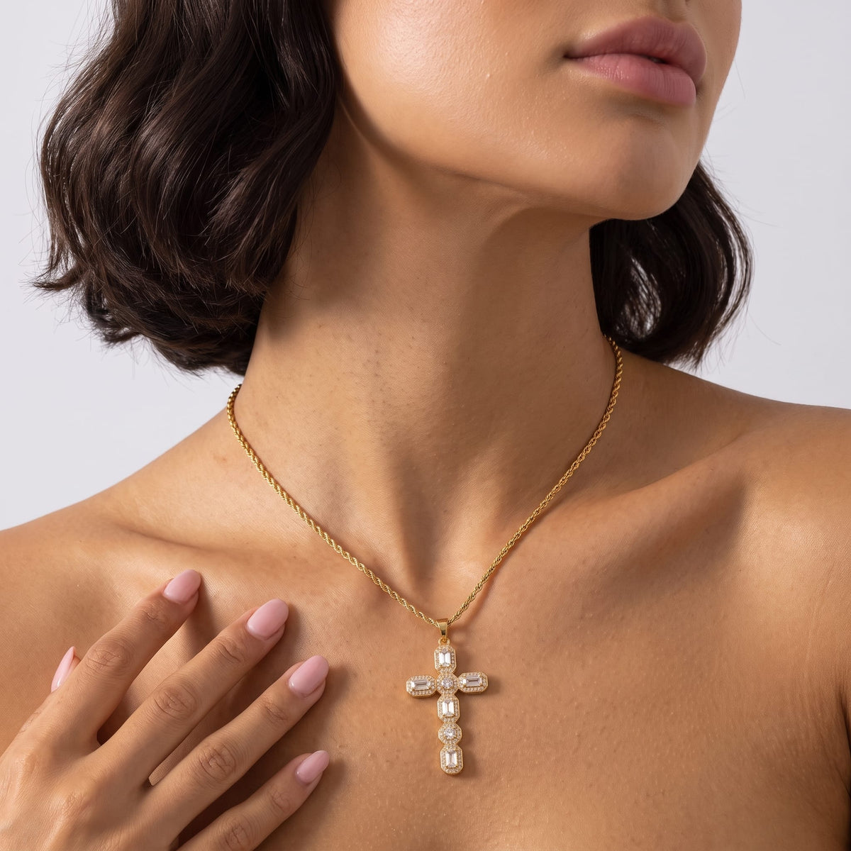 Woman wearing the Flavia halo cross gold necklace at the collarbone with short dark hair