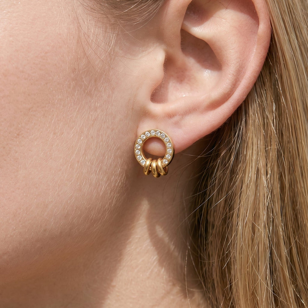 Woman wearing the Gabrielle triple ring gold earrings on the ear