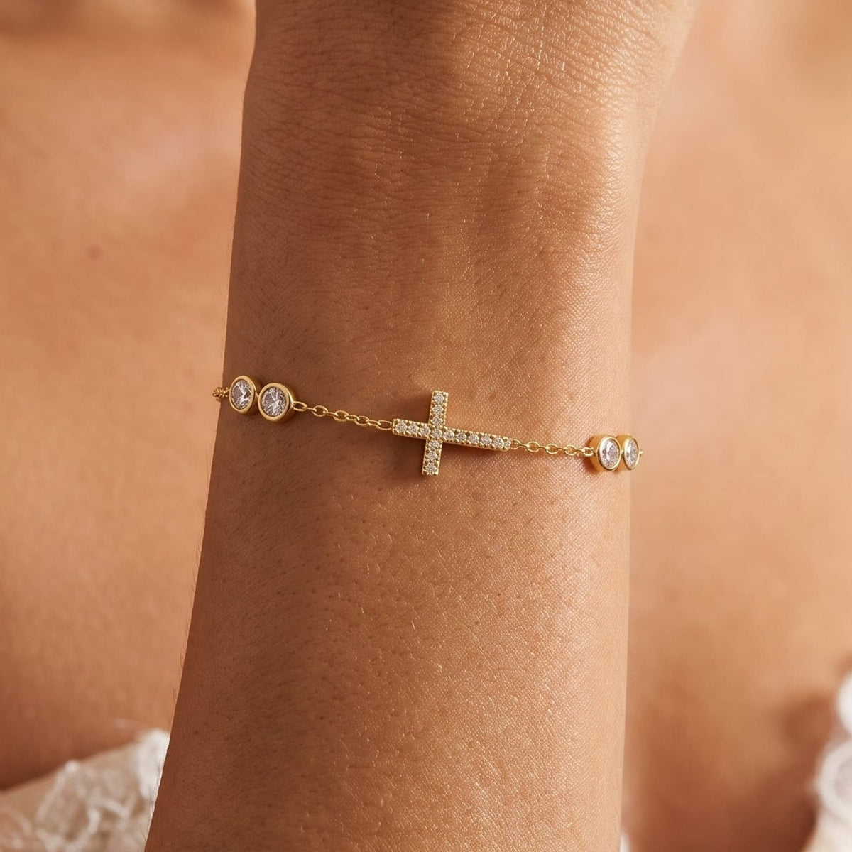 Woman wearing the Giulia sideways cross gold bracelet on the wrist, featuring round crystals
