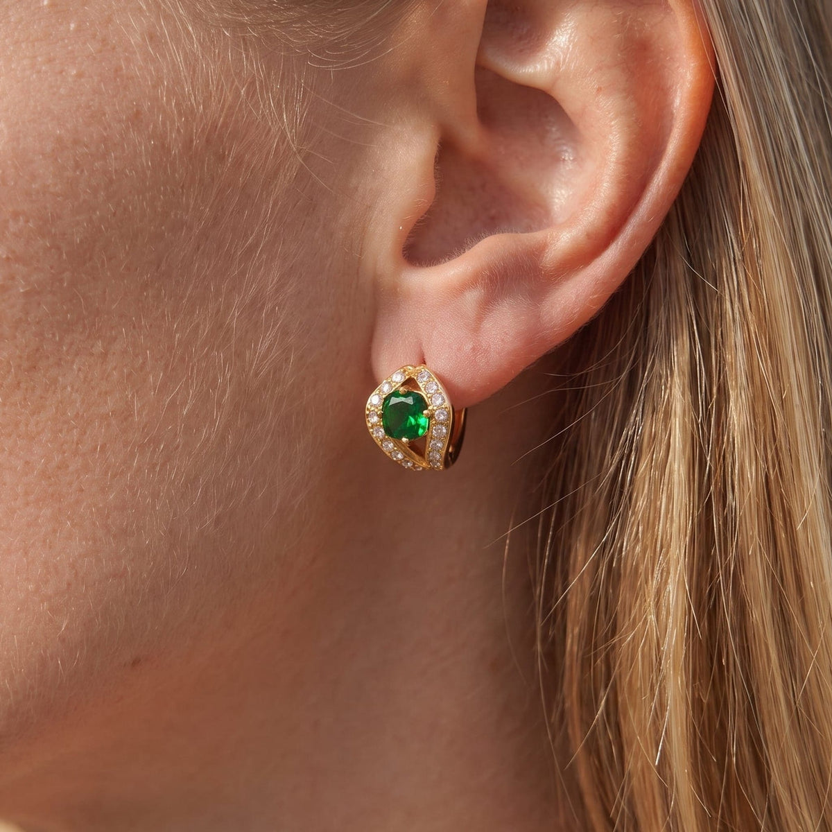Woman wearing the Ilaria green halo gold earrings on the ear