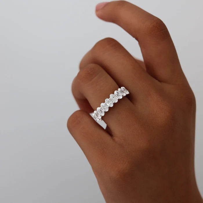Hand wearing the Amelia eternity silver ring with a full row of oval crystals against a grey background