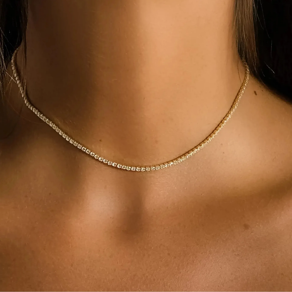 Woman wearing the Amélie tennis choker in gold, a row of zircon crystals at the throat