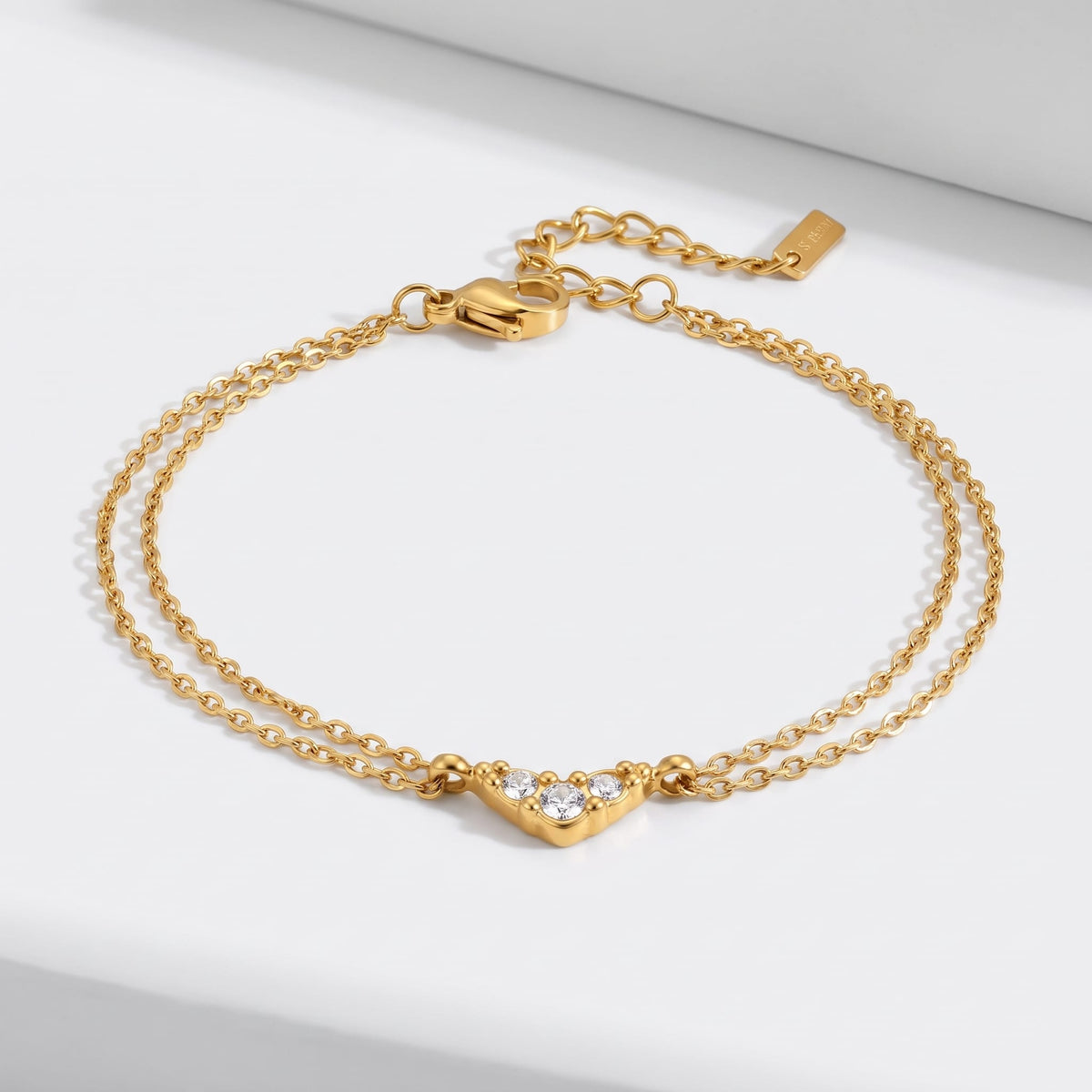 Inès crystal chevron gold bracelet on a white surface with the double chain spread out