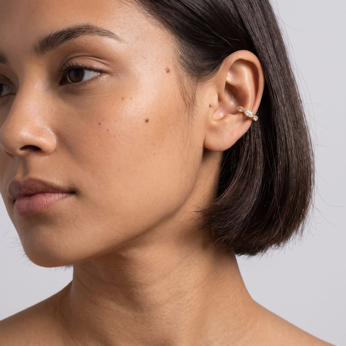 Woman wearing the Irène marquise gold ear cuffs on the ear with a short dark bob