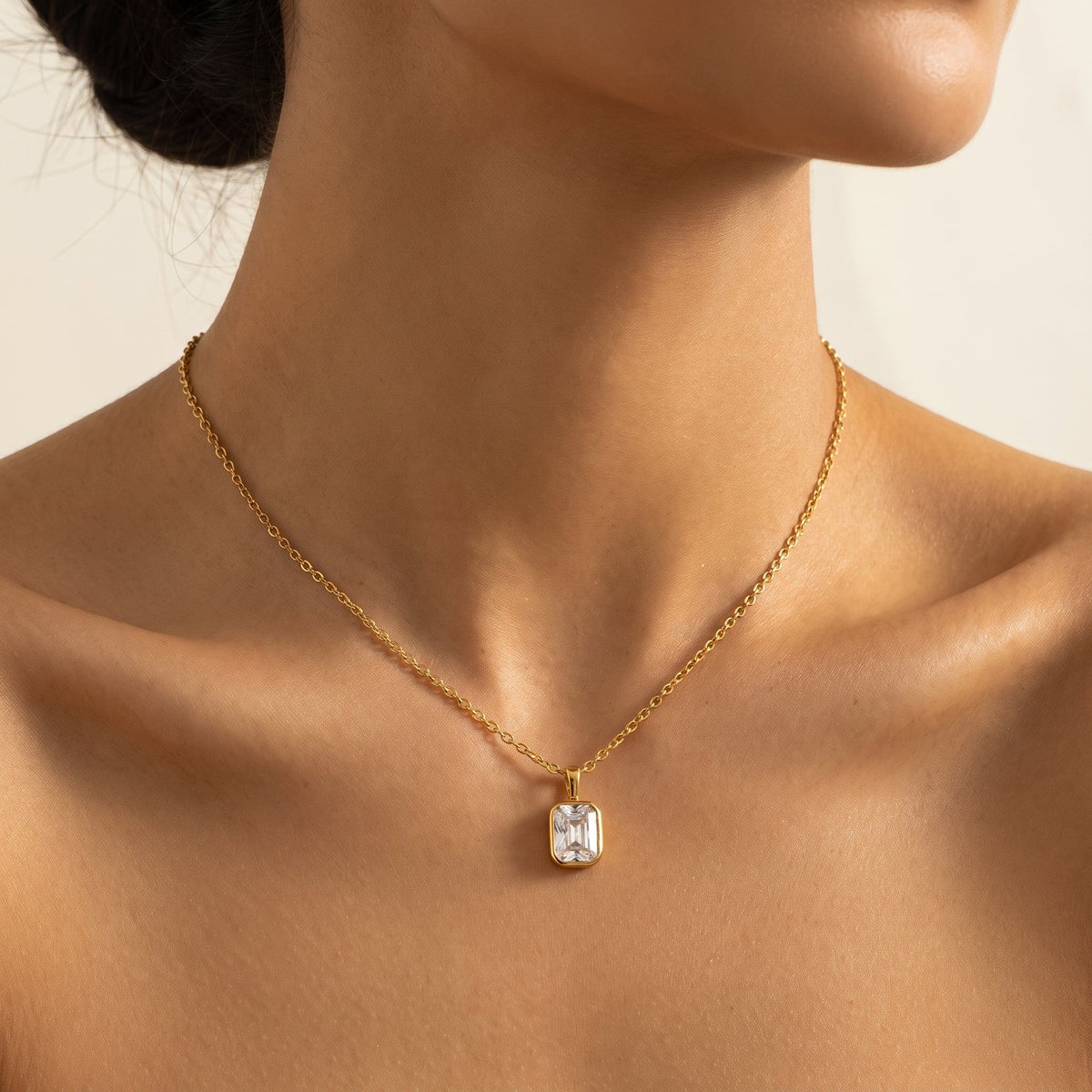 Woman wearing the Livia emerald-cut solitaire gold necklace at the collarbone