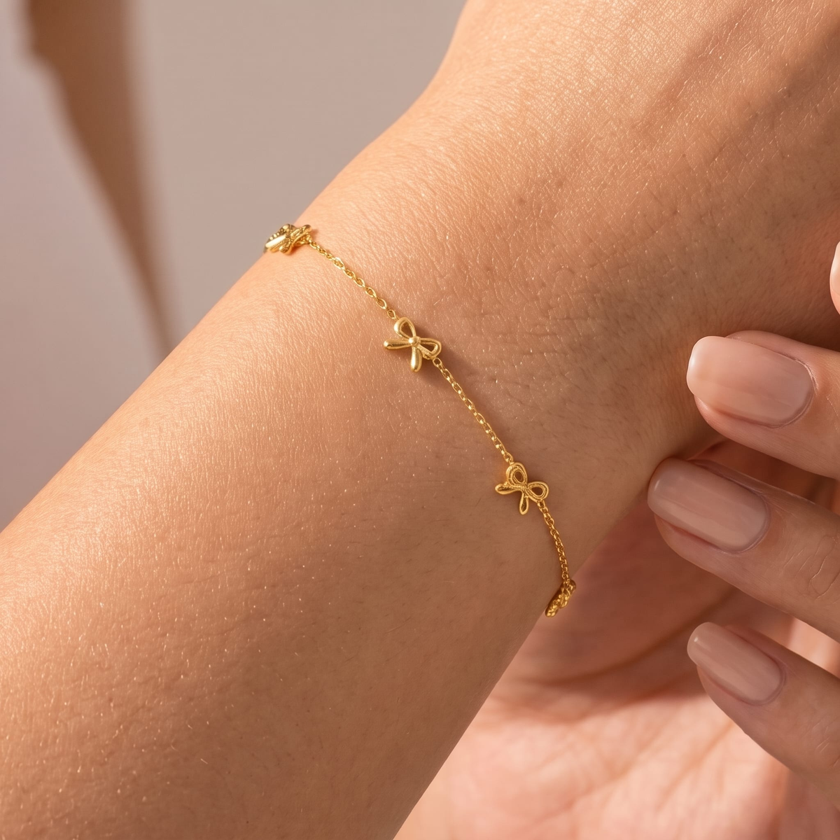 Woman wearing the Lucienne gold bow bracelet with small bows spaced along a fine chain