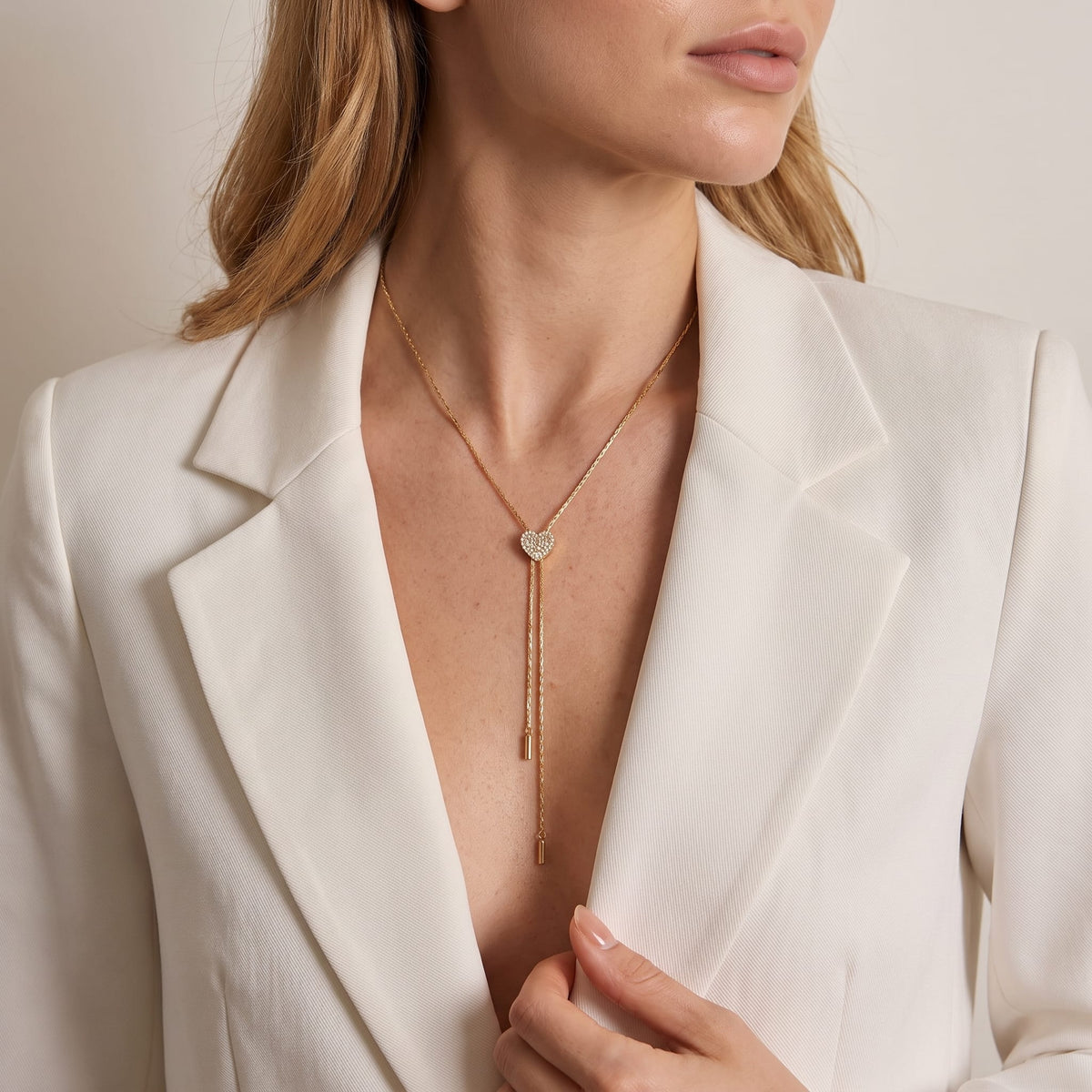 Woman wearing the Maëlys heart slider gold necklace at the collarbone with a white blazer