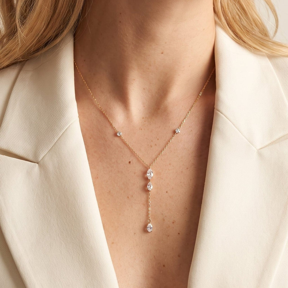 Woman wearing the Mireille marquise drop gold necklace at the collarbone, in a white blazer
