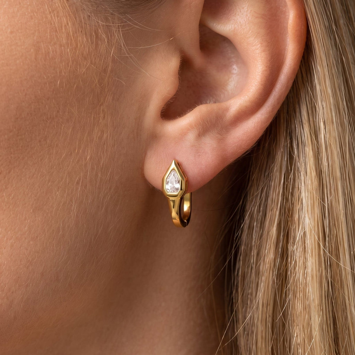 Woman wearing the Mireille pear bezel gold earrings on the ear