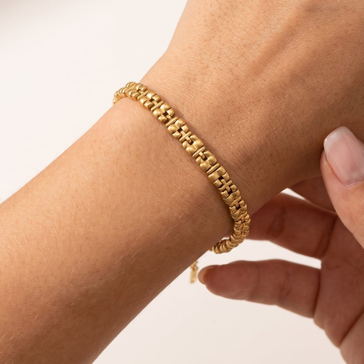 Woman wearing the Nicoletta puffed link gold bracelet on the wrist, adjusting it with her hand