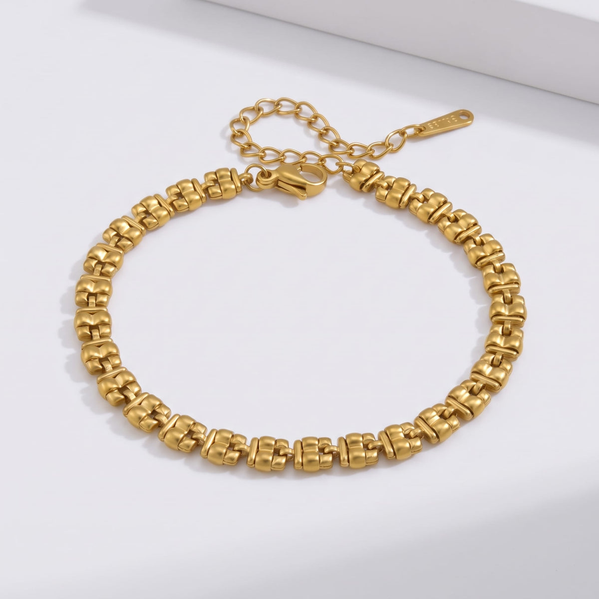Nicoletta puffed link gold bracelet on a white surface with extended clasp chain