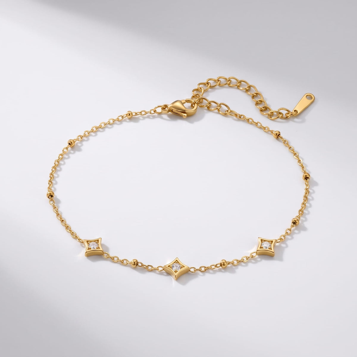 Océane star station gold bracelet on a white surface with soft directional shadows