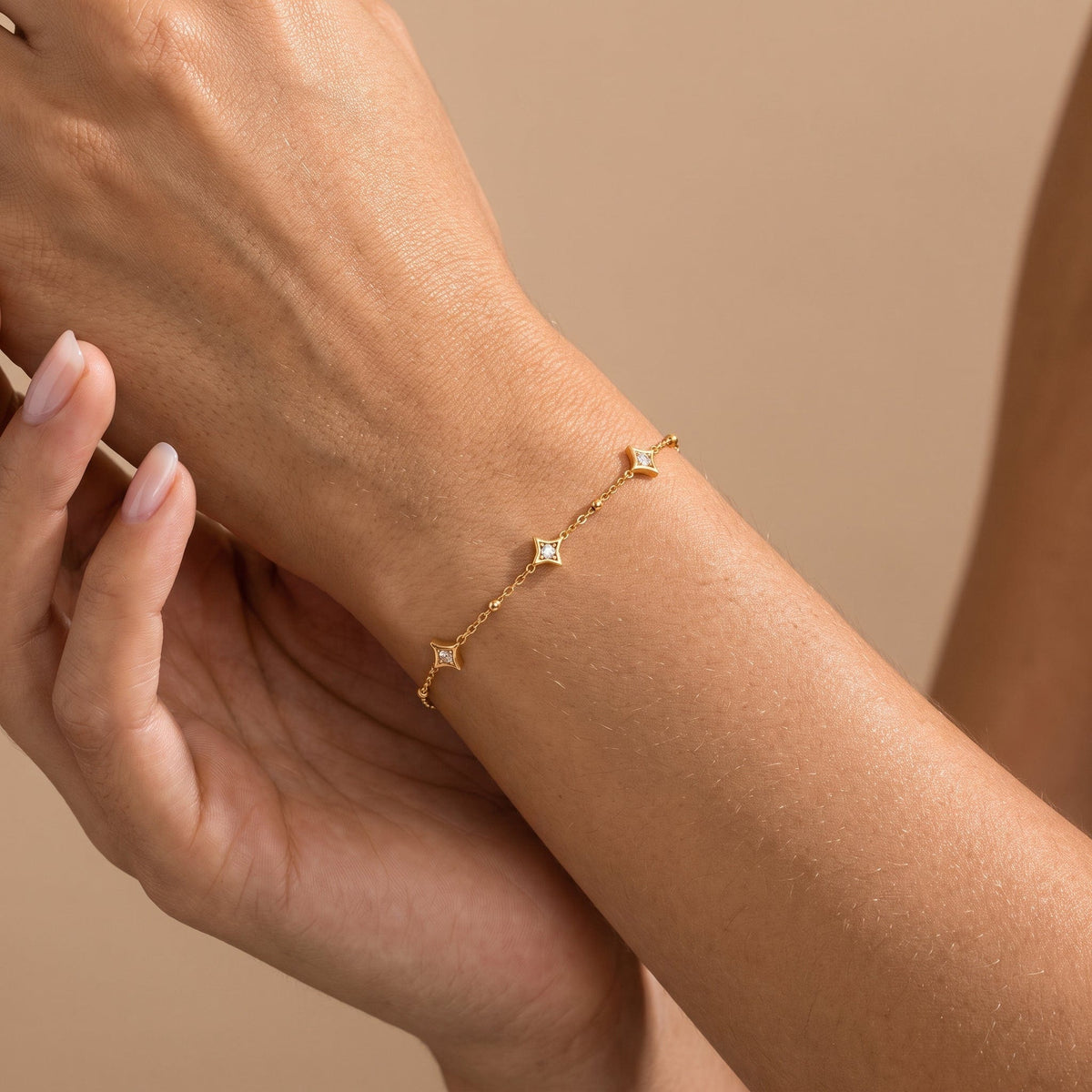 Wider view of a woman wearing the Océane star station gold bracelet on the wrist