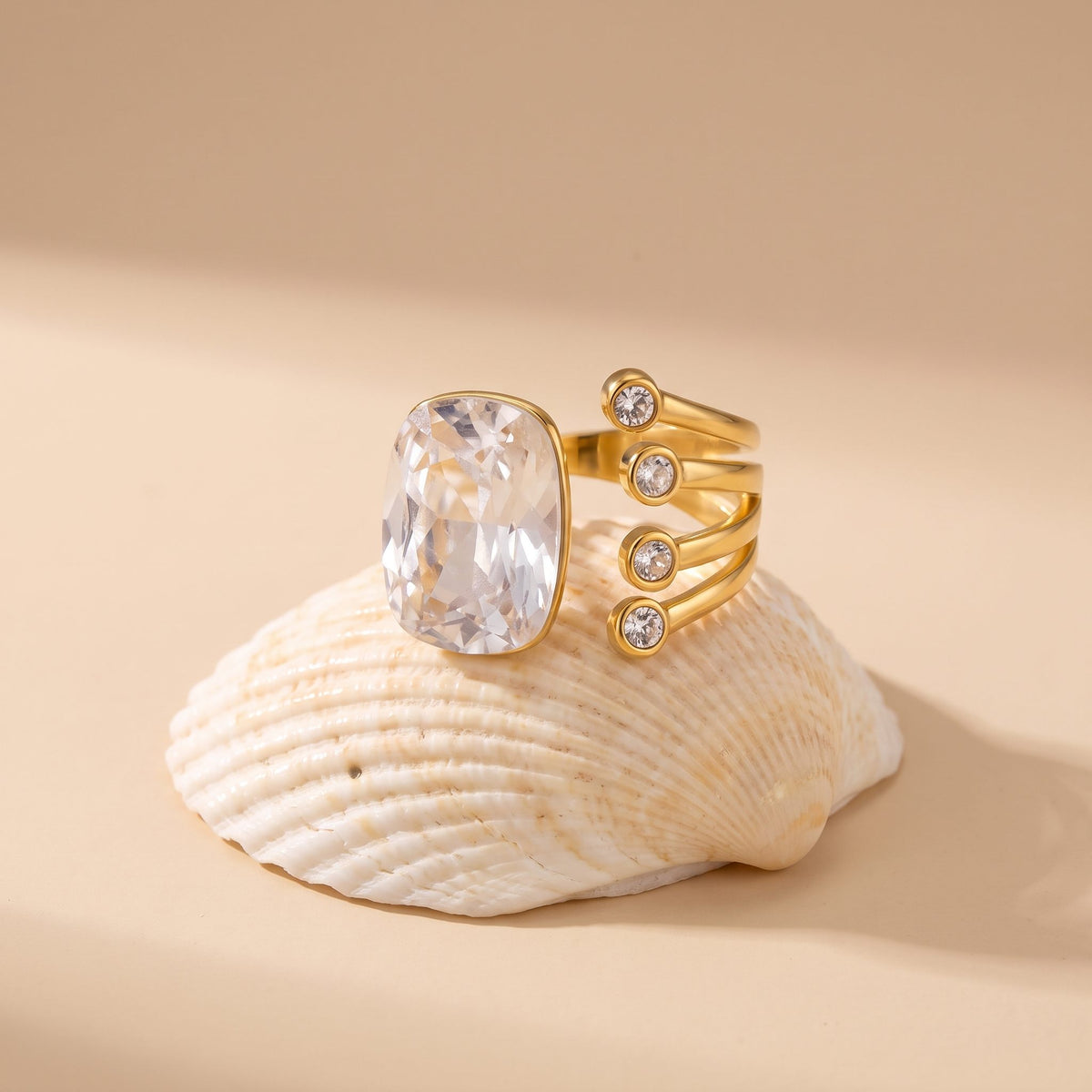The Olivia cushion crystal gold ring resting on a seashell