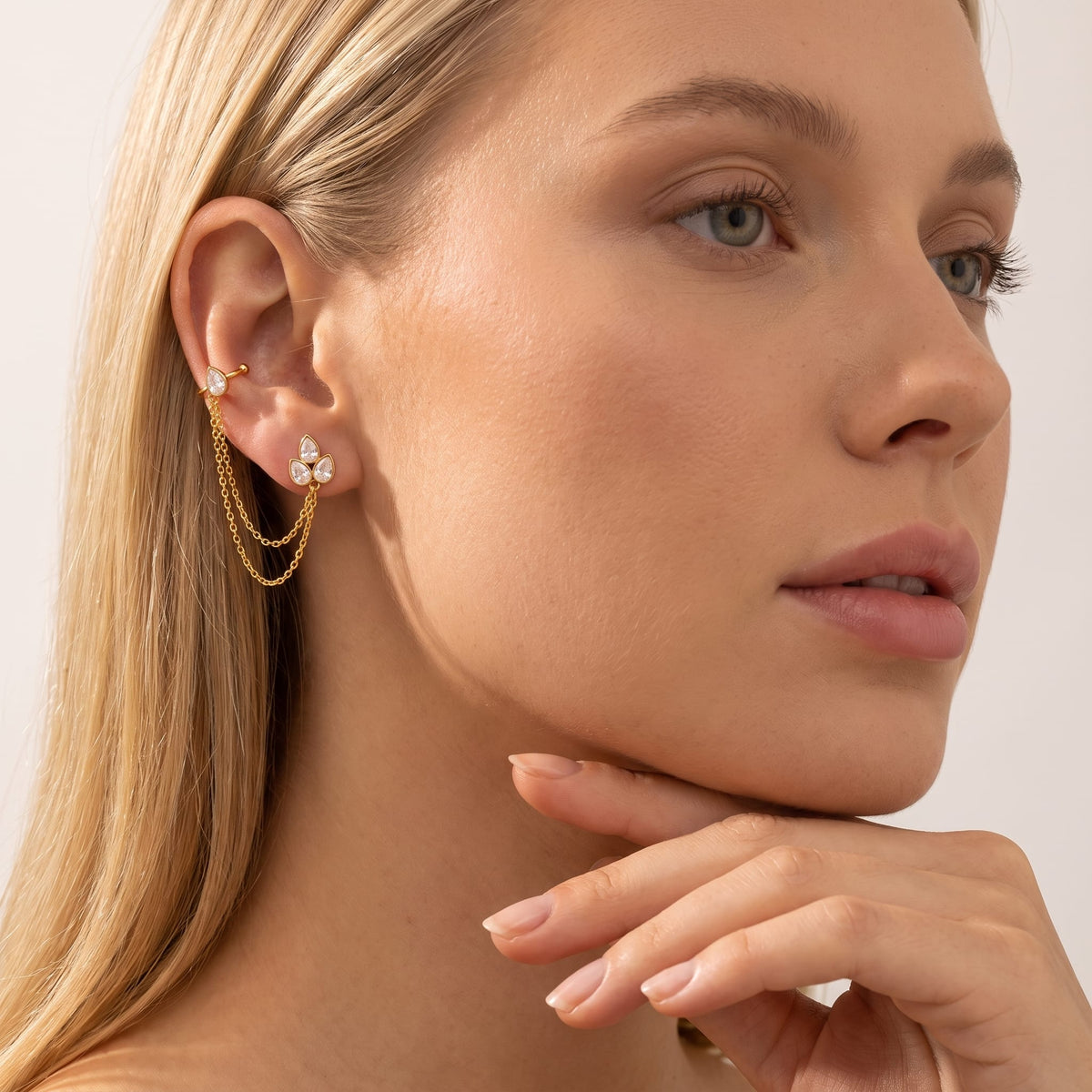 Woman wearing the Ophélie cuff chain gold earrings on her ear touching her chin
