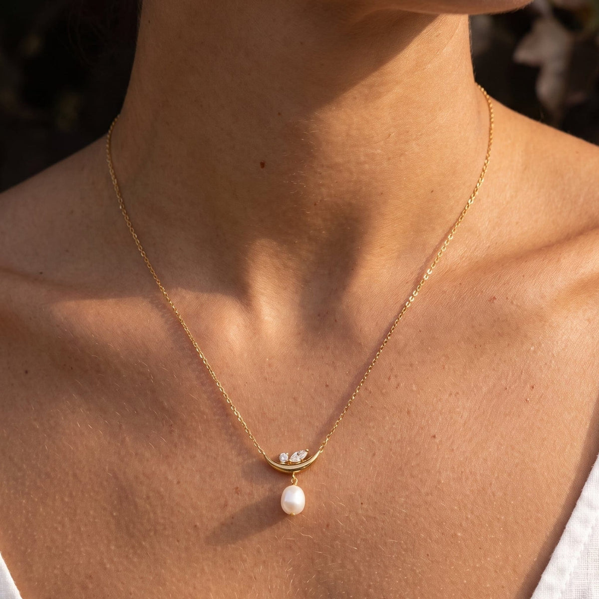 Woman wearing the Pauline moon pearl gold necklace at the collarbone