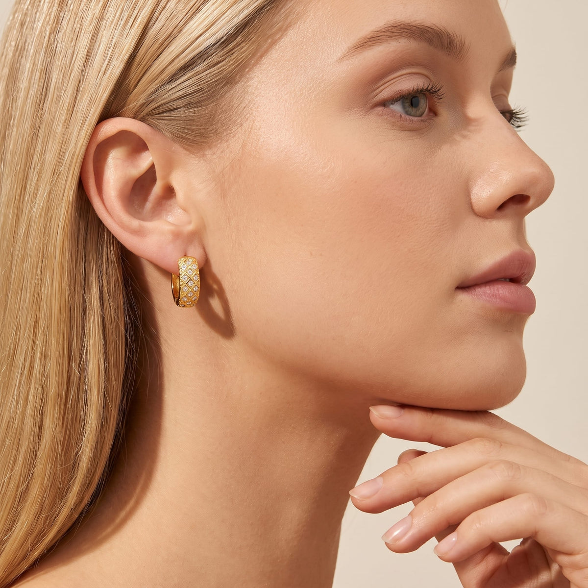 Woman wearing the Solène lattice hoop gold earrings on her ear resting her hand under her chin