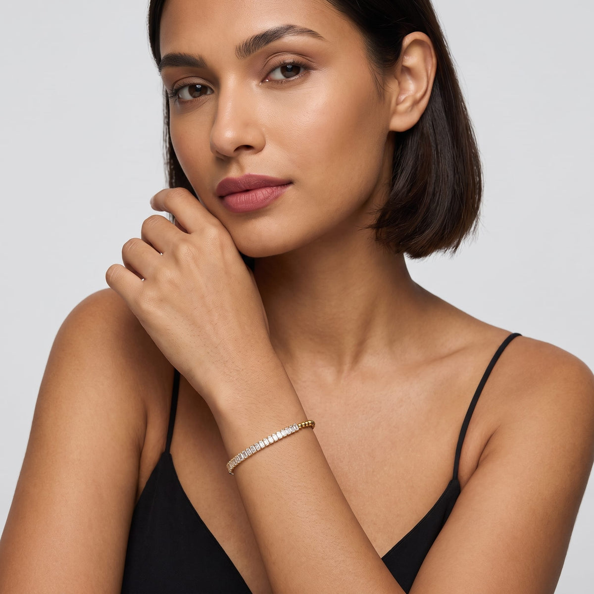 Woman wearing the Vida baguette bead gold bracelet on the wrist in a black tank top
