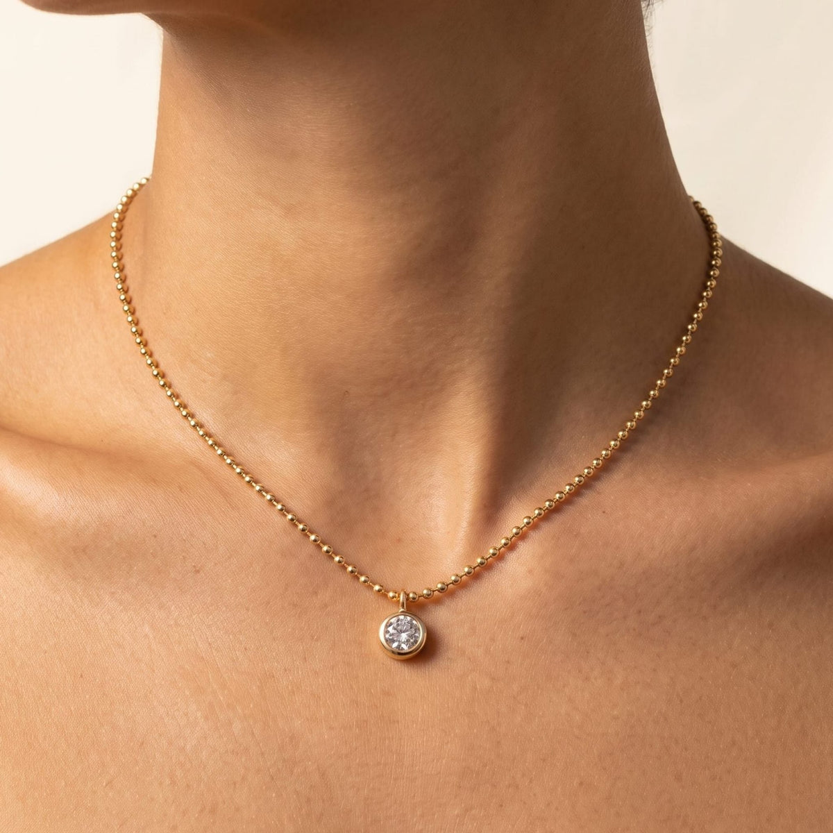 Close-up of a woman wearing the Vida crystal bezel gold necklace at the base of her neck