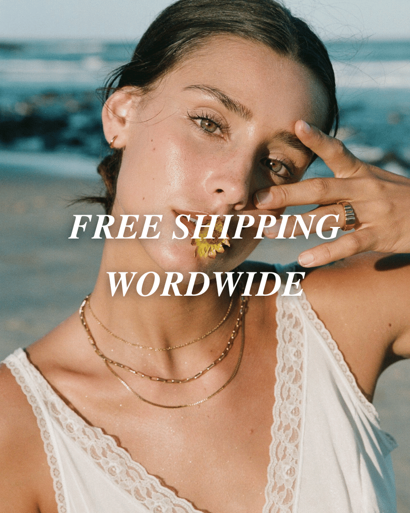 Woman at the beach wearing layered gold necklaces, captioned free shipping worldwide