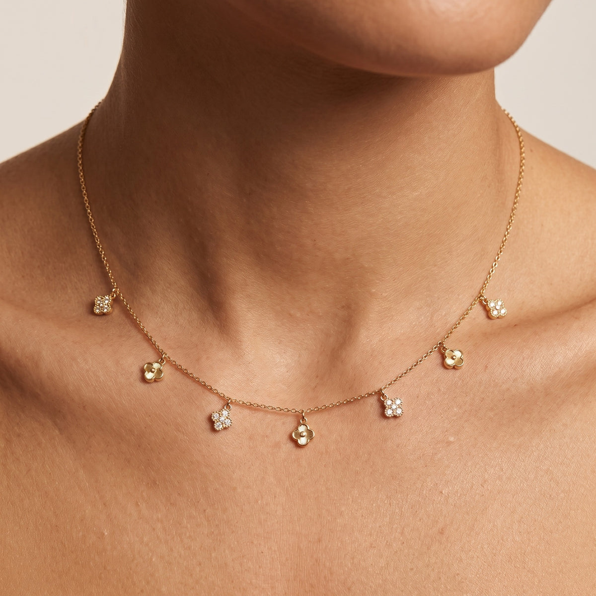 Woman wearing the Amelia crystal flower gold necklace, pavé and polished flower charms