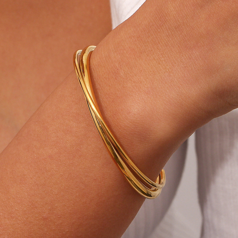 Woman wearing the Rianne layered gold bangle of interlocking polished bands on the wrist