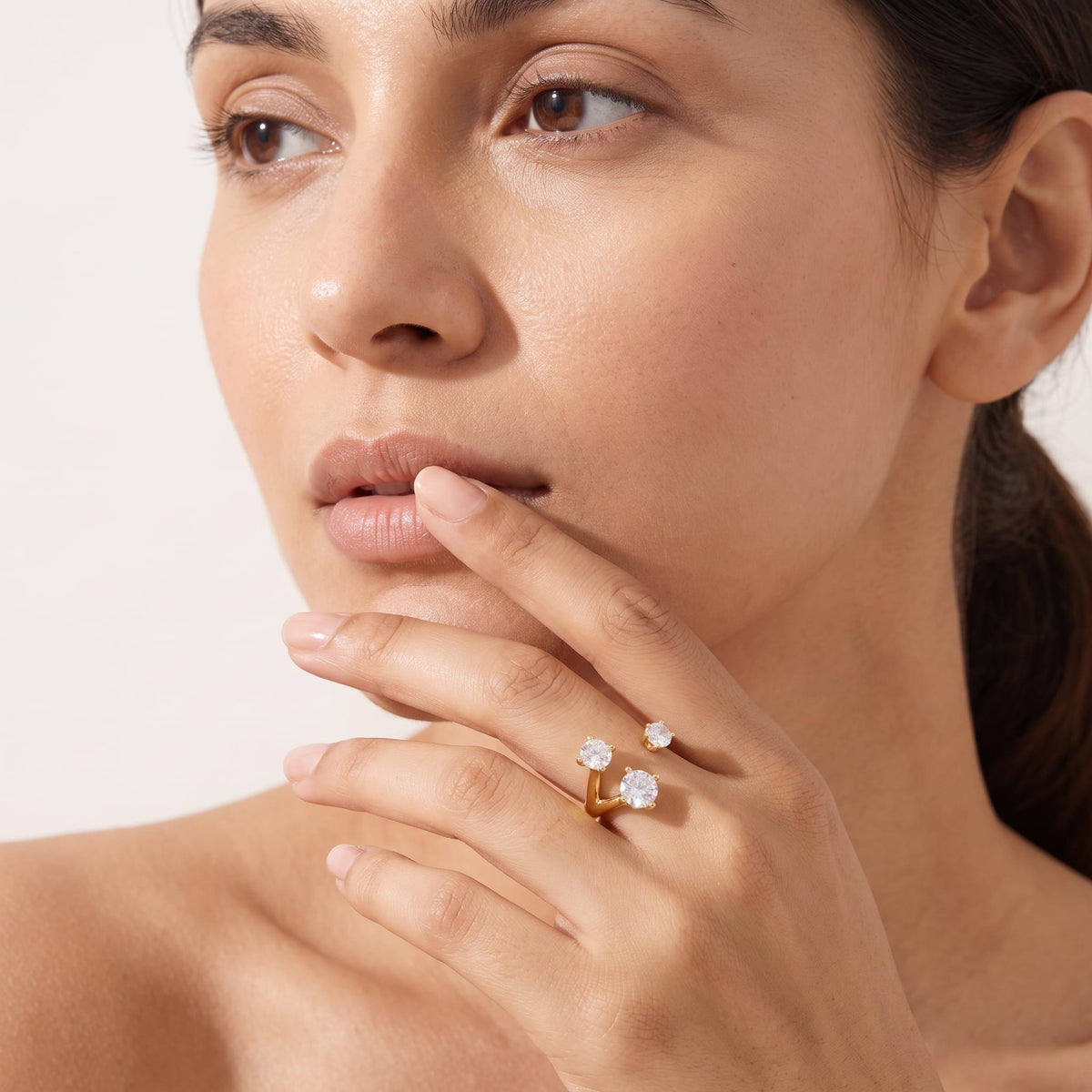 Woman wearing the Adriana three stone gold ring on the hand while posing close up