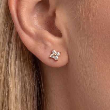 Blonde woman wearing the Agathe four-petal crystal clover stud in gold on the earlobe