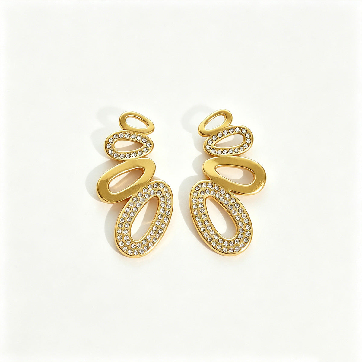 Agathe pavé oval gold earrings, stacked polished and crystal-set ovals, on a white background